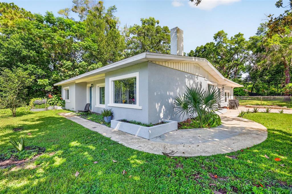 A gray single-story house with a chimney, a concrete walkway, and a small planter box — 428 RUTH ST, LONGWOOD, FL