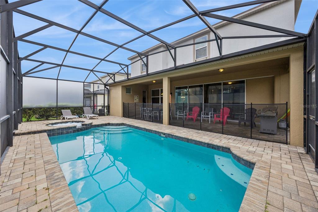 A screened-in patio features a swimming pool, a hot tub, and outdoor seating — 9008 SUNSHINE RIDGE LOOP, KISSIMMEE, FL