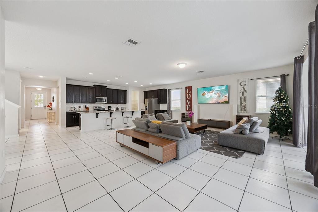 An open-concept living room and kitchen with white tile floors and dark wood cabinetry — 9008 SUNSHINE RIDGE LOOP, KISSIMMEE, FL