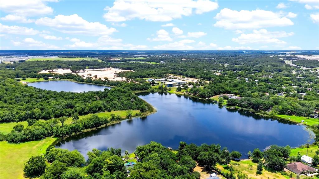 An aerial view shows a large lake surrounded by dense trees and green fields — 4162 LAUGHLIN ROAD, MOUNT DORA, FL