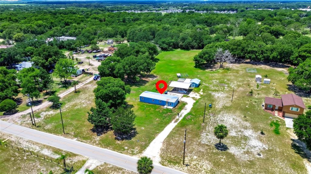 An aerial view shows a blue rectangular building on a large, grassy, tree-lined lot — 4162 LAUGHLIN ROAD, MOUNT DORA, FL