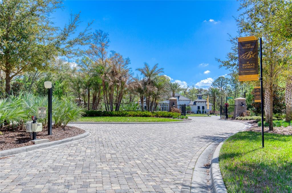 A paved driveway leads to the gated entrance of a residential community with palm trees — 1801 ADRIAN CREEK BOULEVARD, PORT ORANGE, FL