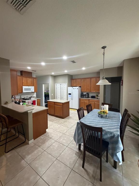 A kitchen with wood cabinets, a central island, and an adjacent dining area with tile floors — 430 MERLOT DRIVE, OCOEE, FL