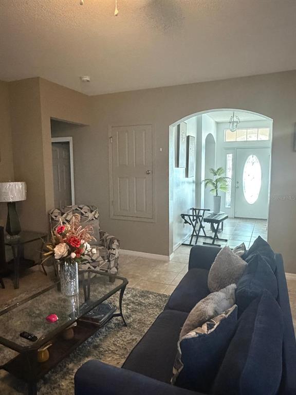 A living room features a blue sofa, a glass coffee table, and an arched entryway — 430 MERLOT DRIVE, OCOEE, FL