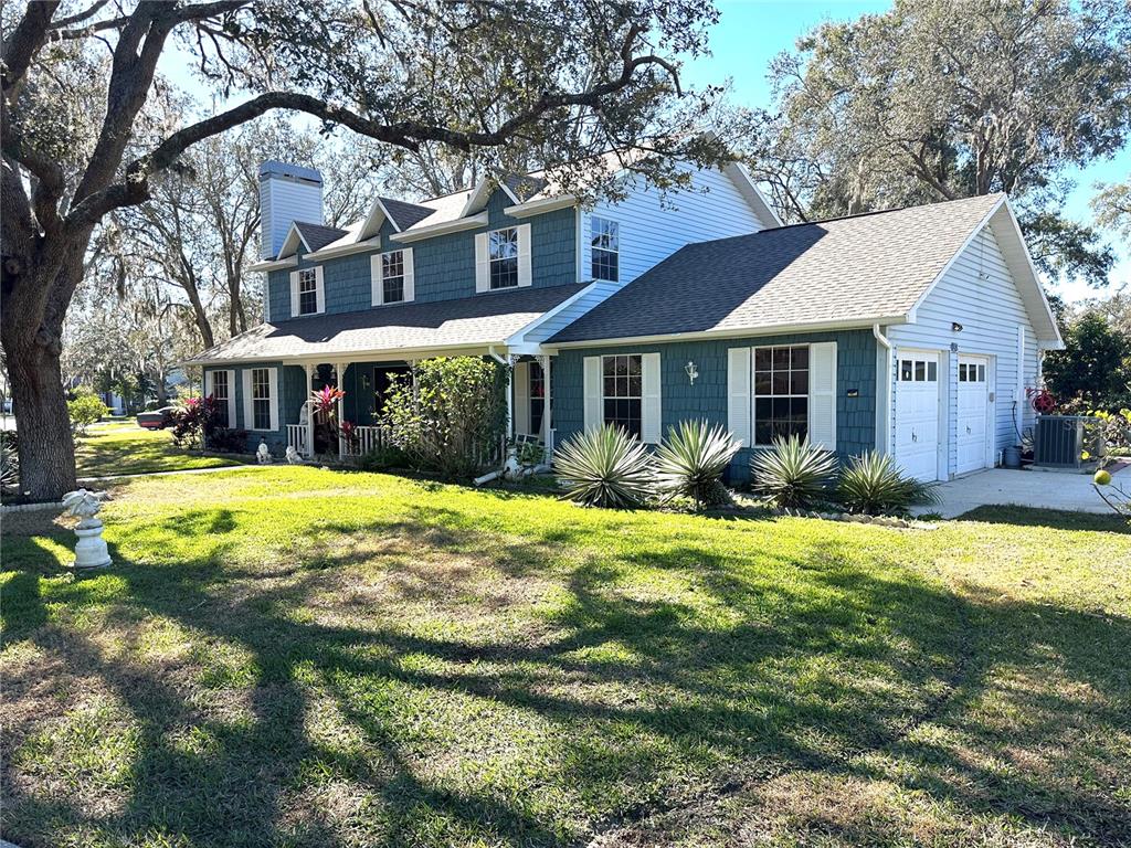 A two-story house with blue siding, a front porch, and an attached two-car garage — 8834 WHISPERING OAKS TRAIL, NEW PORT RICHEY, FL