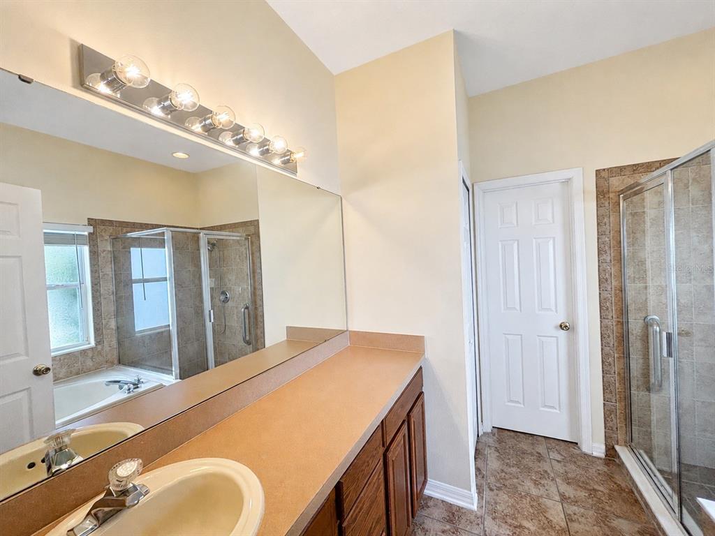 A bathroom features a vanity with a tan countertop, a large mirror, and a shower — 2240 FLORIDA SOAPBERRY BOULEVARD, ORLANDO, FL