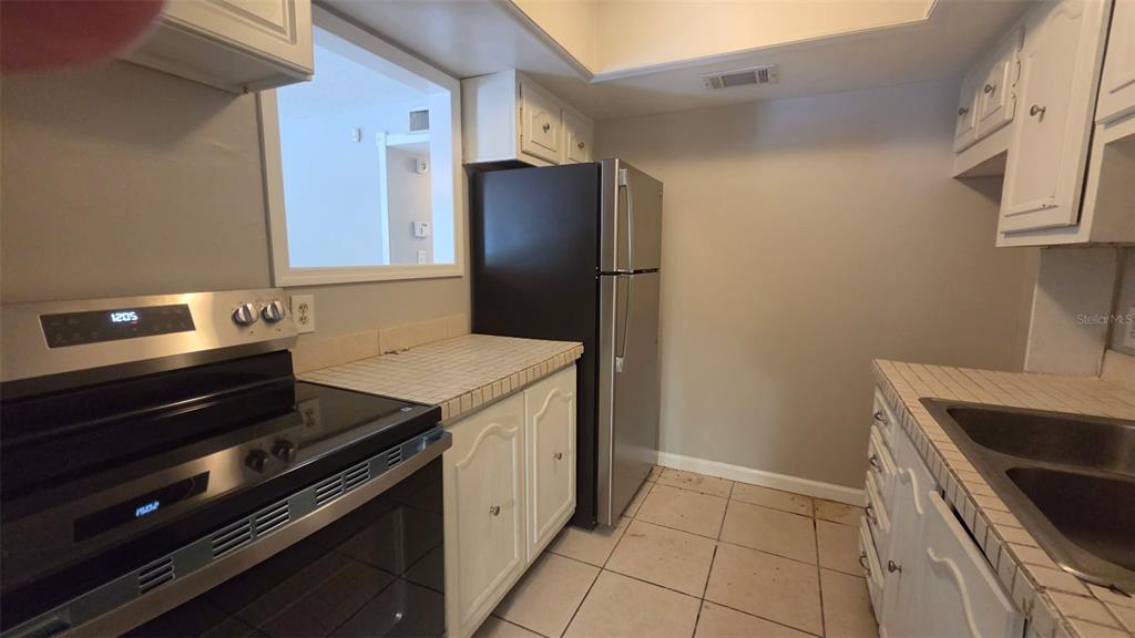 A dining area features beige walls, light-colored floor tiles, and a hanging chandelier — 700 E AIRPORT BOULEVARD UNIT B6, SANFORD, FL