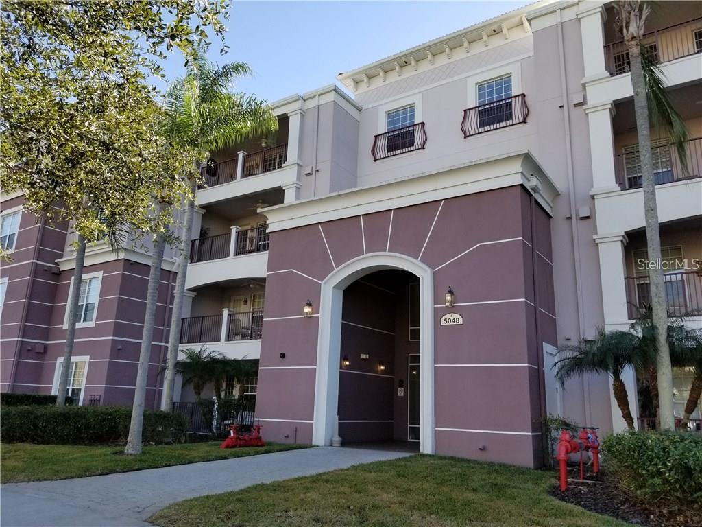 A multi-story apartment building exterior features a central arched entryway and balconies with railings — 5048 SHOREWAY LOOP UNIT 20404, ORLANDO, FL