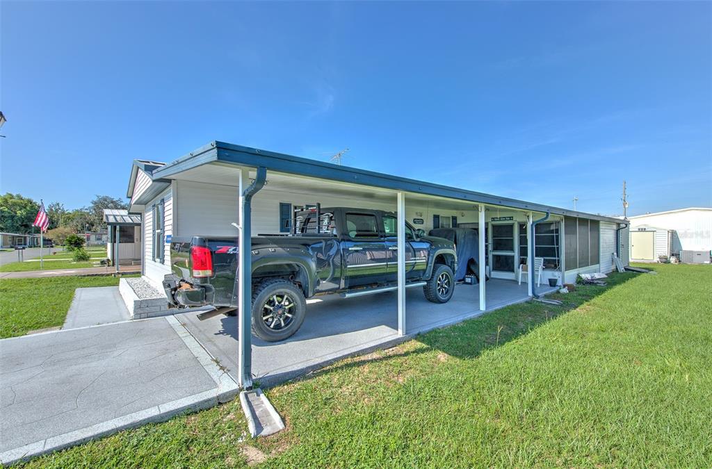 A mobile home with a large carport and a parked pickup truck on a grassy lot — 5309 MONTEGO DRIVE, ZEPHYRHILLS, FL