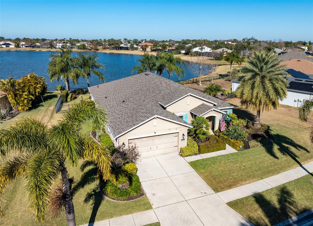 An aerial view shows a single-story house with a two-car garage near a lake — 5431 SANDY SHELL DRIVE, APOLLO BEACH, FL