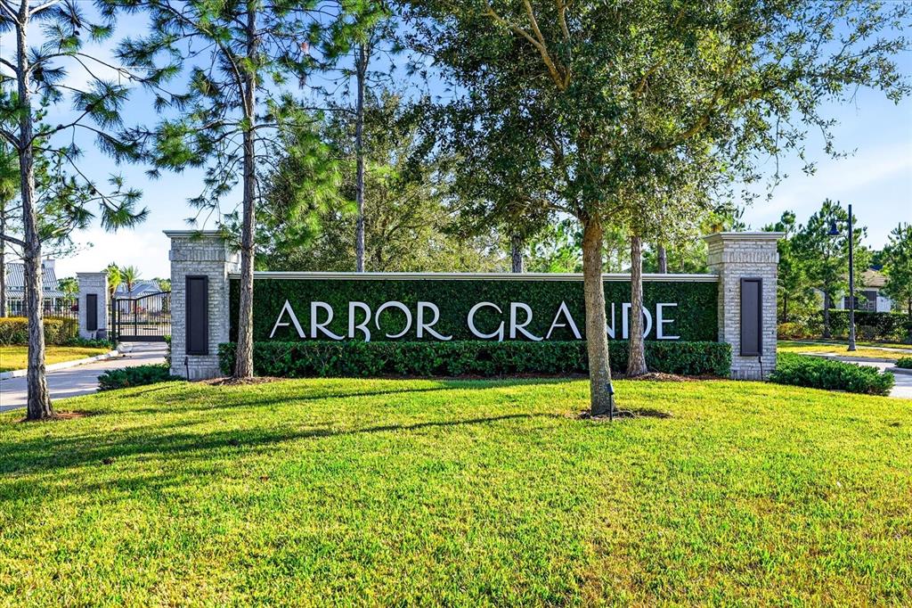 A stone monument sign for Arbor Grande stands on a grassy lawn near trees — 2528 STARWOOD COURT, LAKEWOOD RANCH, FL