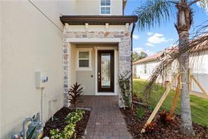 A stone-accented entryway features a dark wood front door and a brick paver walkway — 2528 STARWOOD COURT, LAKEWOOD RANCH, FL