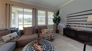 A living room features a sectional sofa, a patterned coffee table, and a slatted wall accent — 2528 STARWOOD COURT, LAKEWOOD RANCH, FL