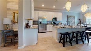 A kitchen features white cabinetry, stainless steel appliances, a center island, and bar stool seating — 2528 STARWOOD COURT, LAKEWOOD RANCH, FL