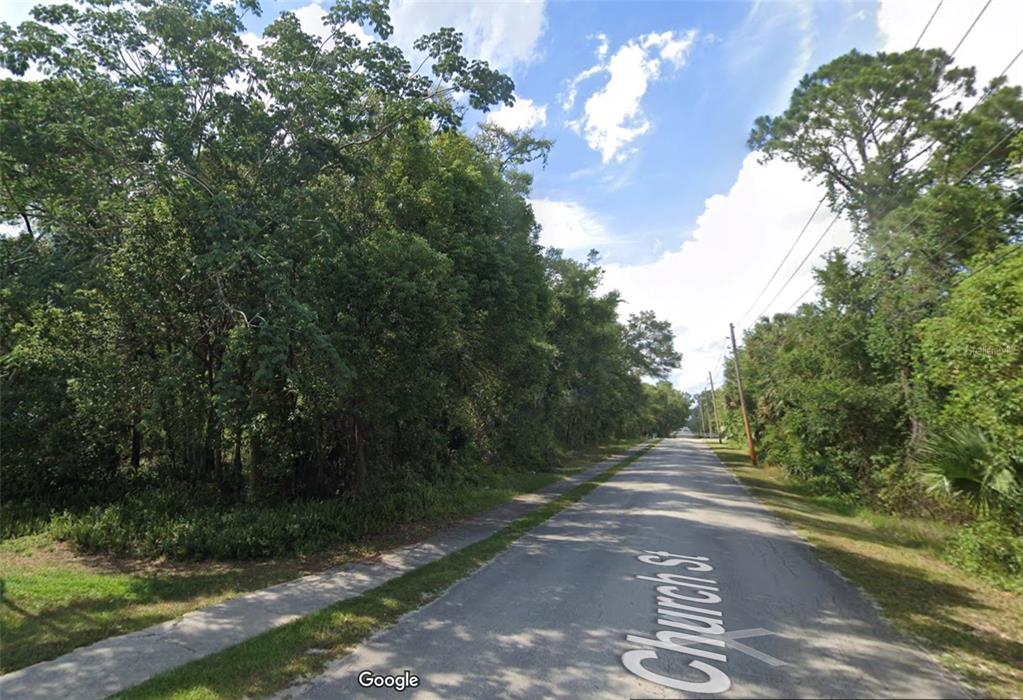 A paved road runs through a wooded area with a sidewalk on the left — 426 CHURCH, LAKE HELEN, FL