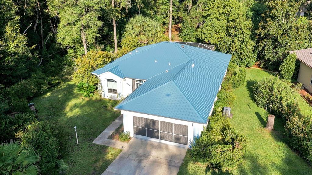 An aerial view of a single-story house with a blue metal roof and garage — 10062 SW 190TH COURT, DUNNELLON, FL