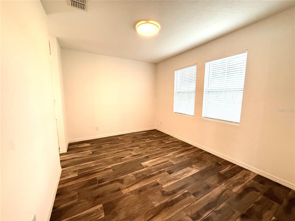 An empty room with white walls, wood-look tile flooring, and two windows with blinds — 15124 LEMON PEEL ALLEY, WINTER GARDEN, FL