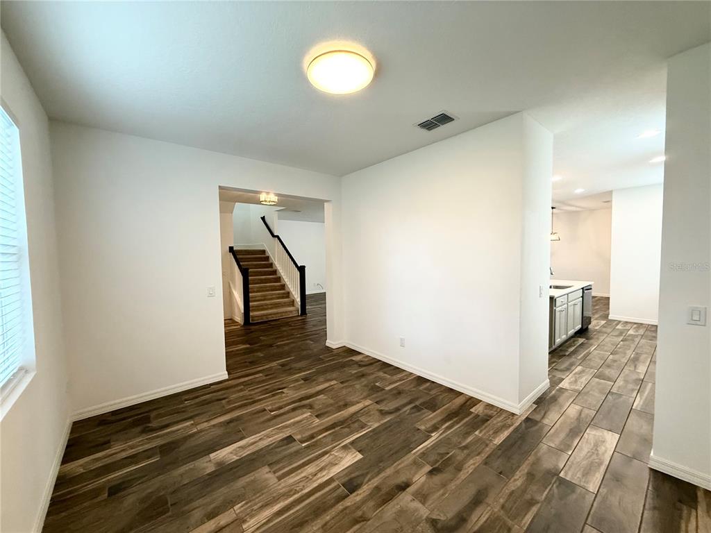 An interior view shows a dining area with wood-look tile floors leading to a staircase — 15124 LEMON PEEL ALLEY, WINTER GARDEN, FL