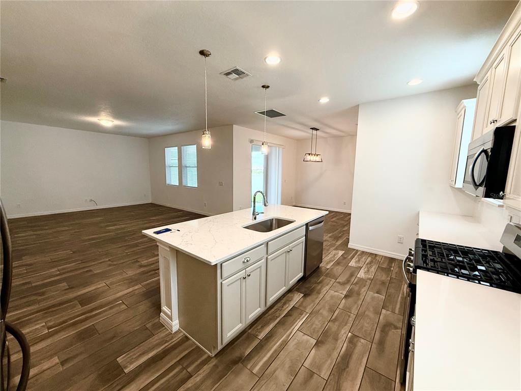 A kitchen with a white quartz island, light cabinetry, and wood-look flooring in an open space — 15124 LEMON PEEL ALLEY, WINTER GARDEN, FL