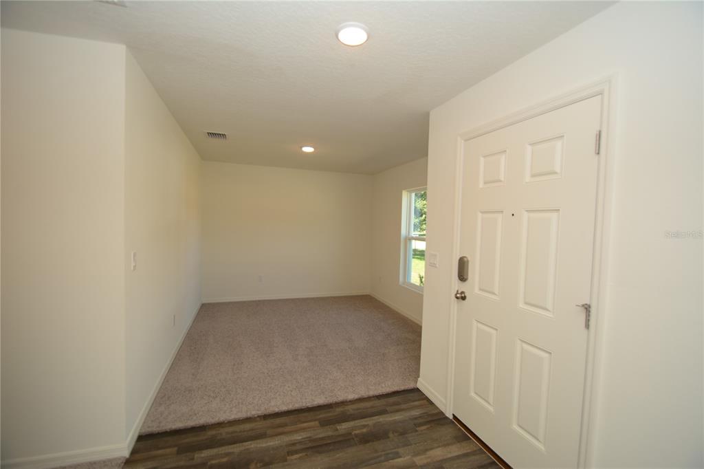 An entryway leads into a carpeted room with white walls and a single window — 93 PANORAMA DRIVE, PALM COAST, FL