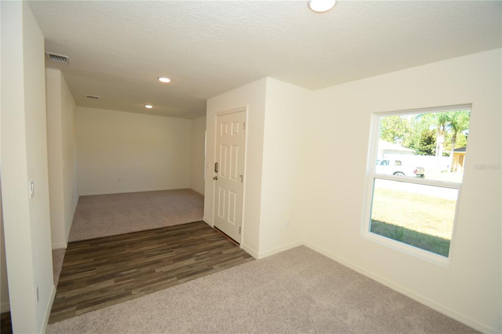 An interior view shows a room with carpeted and wood-look flooring, a door, and a window — 93 PANORAMA DRIVE, PALM COAST, FL