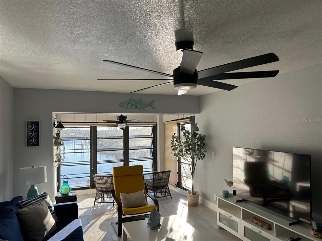 A living room with a ceiling fan, yellow chair, and large windows overlooking the water — 1008 APOLLO BEACH BOULEVARD UNIT 210, APOLLO BEACH, FL