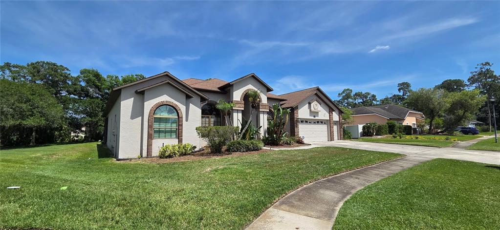 A single-story house with a beige stucco exterior, arched windows, and a two-car garage — 3904 HIDDEN SPRING PLACE, VALRICO, FL