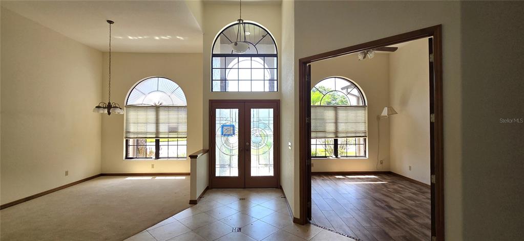 An entryway with tile floors leads to a carpeted dining area and a wood-floored room — 3904 HIDDEN SPRING PLACE, VALRICO, FL
