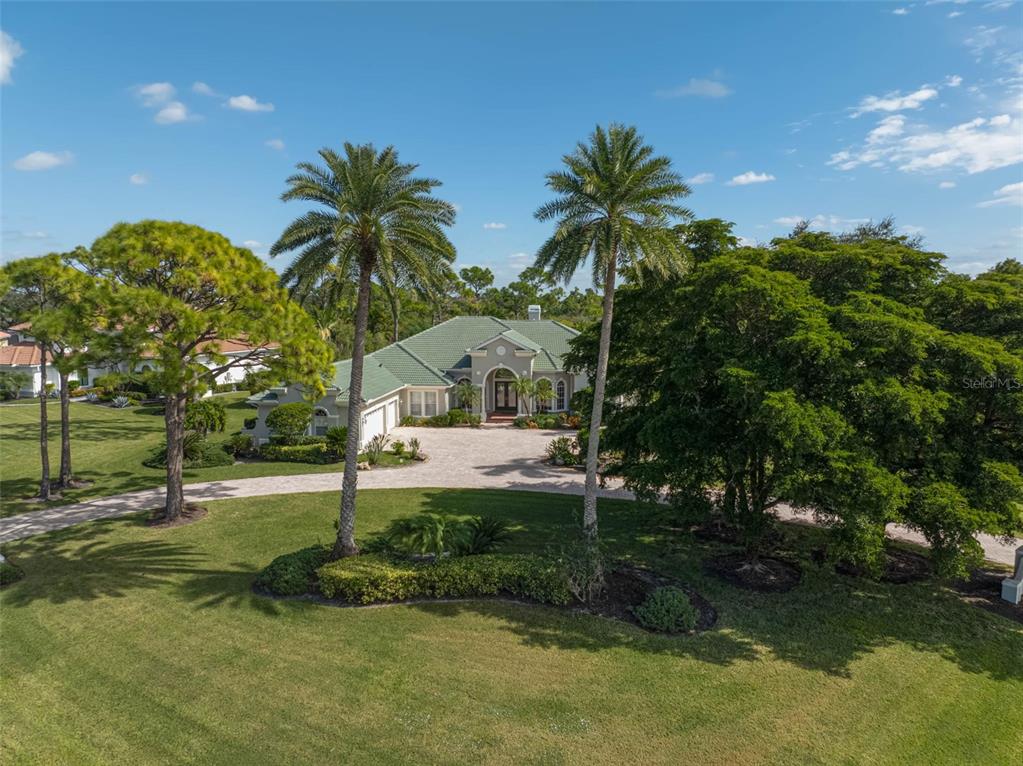 An aerial view of a single-story house with a green roof and a circular driveway — 538 DOVE POINTE DRIVE, OSPREY, FL