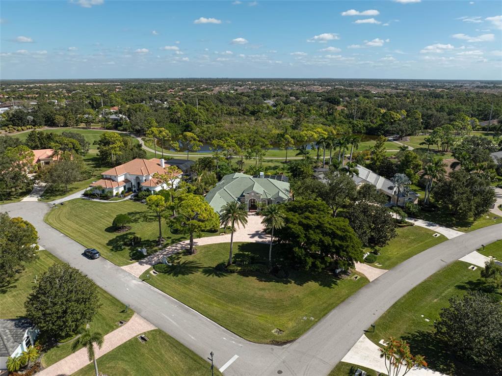 An aerial view shows a large house with a green roof surrounded by landscaped lawns — 538 DOVE POINTE DRIVE, OSPREY, FL