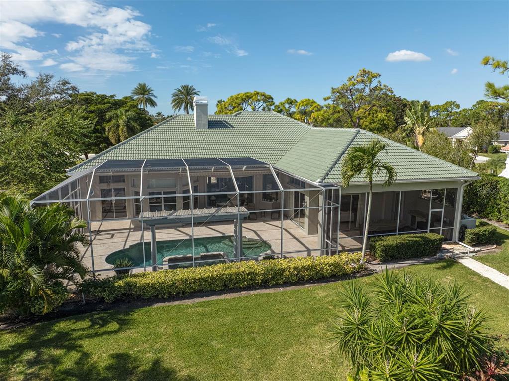 An aerial view of a house with a green tile roof and a screened-in pool — 538 DOVE POINTE DRIVE, OSPREY, FL