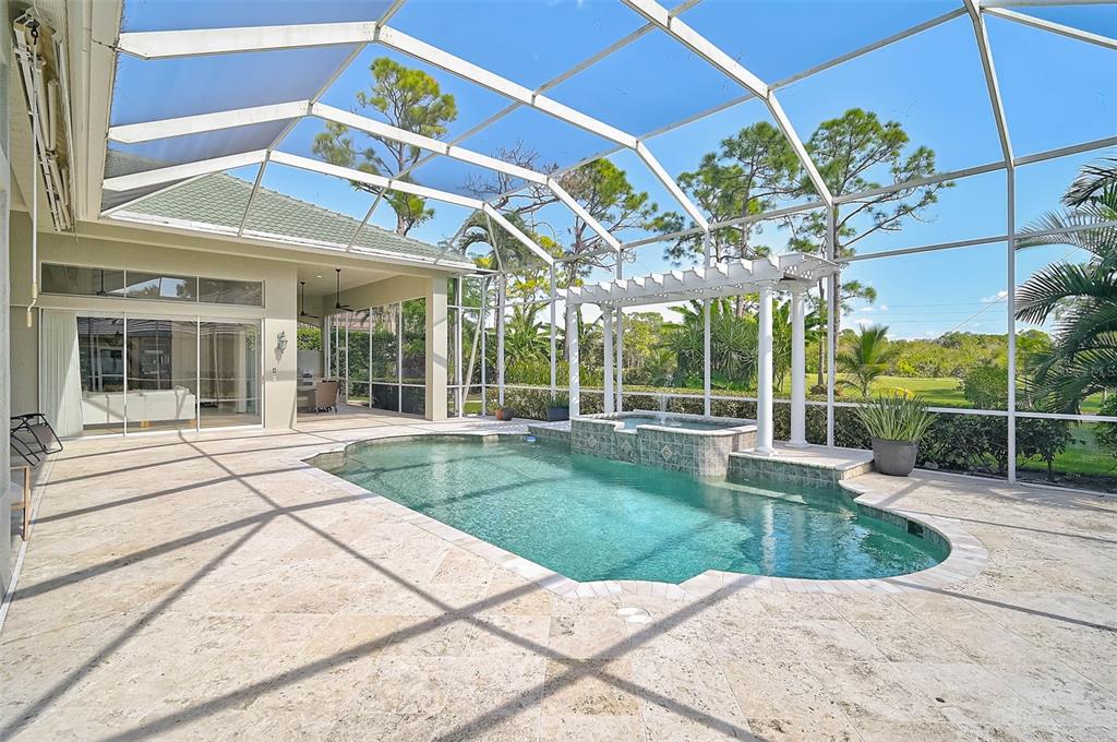 A screened-in patio features a swimming pool, a spa with a pergola, and stone pavers — 538 DOVE POINTE DRIVE, OSPREY, FL