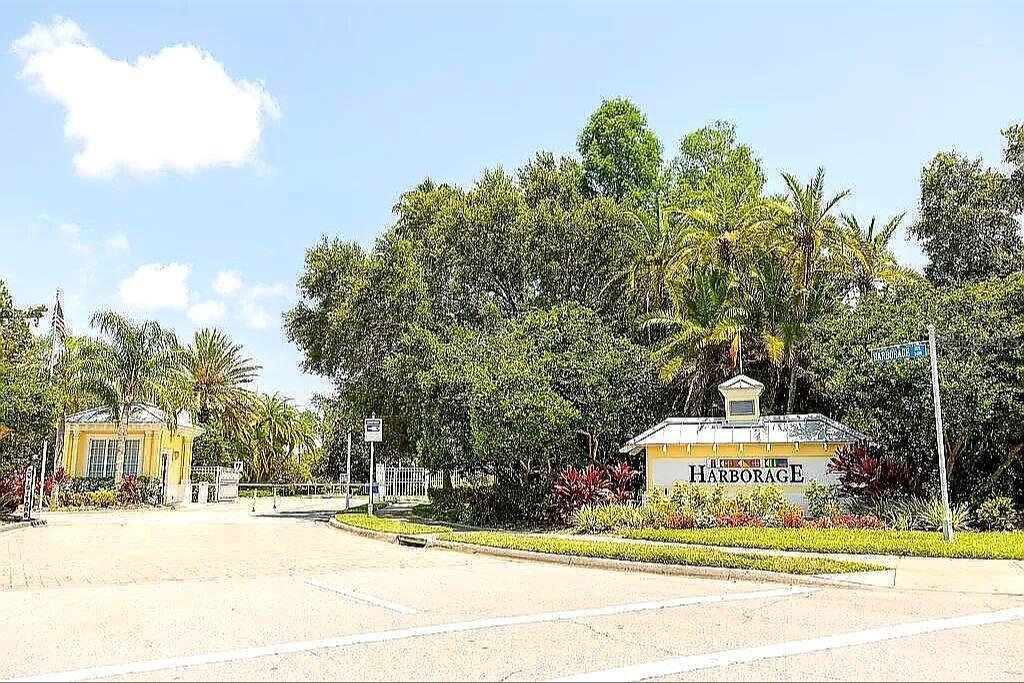 The entrance to a residential community features a yellow gatehouse and a sign reading Harborage — 5662 WHITEHEAD STREET, BRADENTON, FL