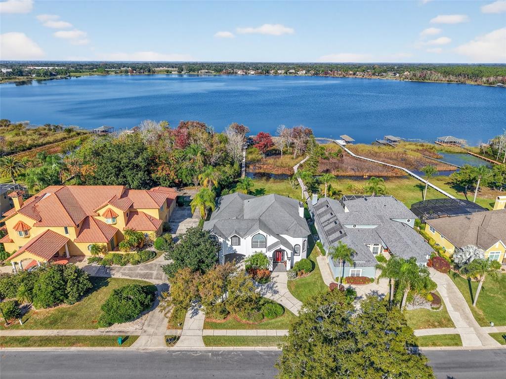 An aerial view shows three houses with driveways and lawns bordering a large lake — 1741 EDGEWATER DRIVE, MOUNT DORA, FL
