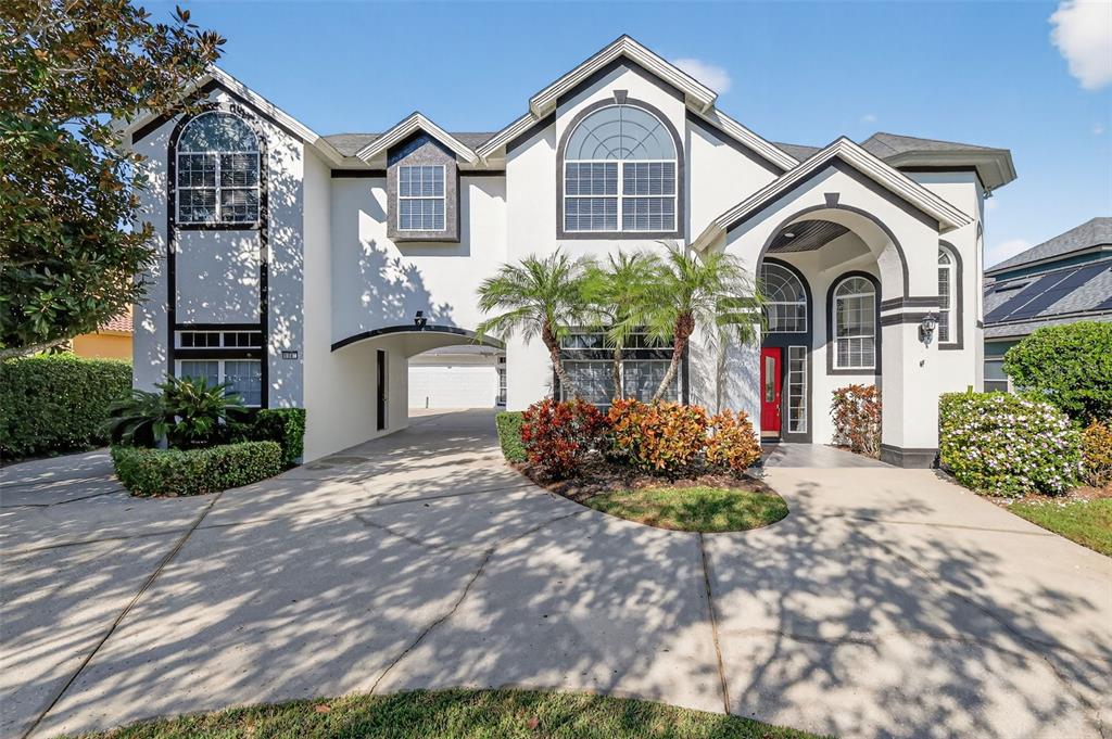A two-story white house with a red front door and a covered driveway entrance — 1741 EDGEWATER DRIVE, MOUNT DORA, FL