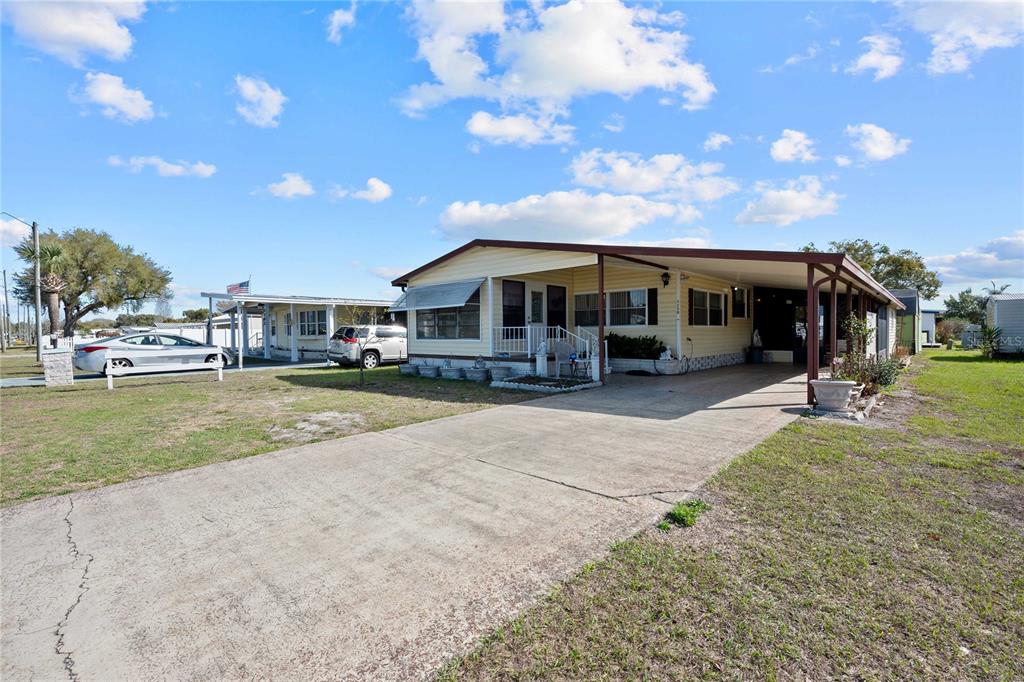 An aerial view shows a yellow mobile home with a carport and a concrete driveway — 5250 DEAN DAIRY ROAD, ZEPHYRHILLS, FL