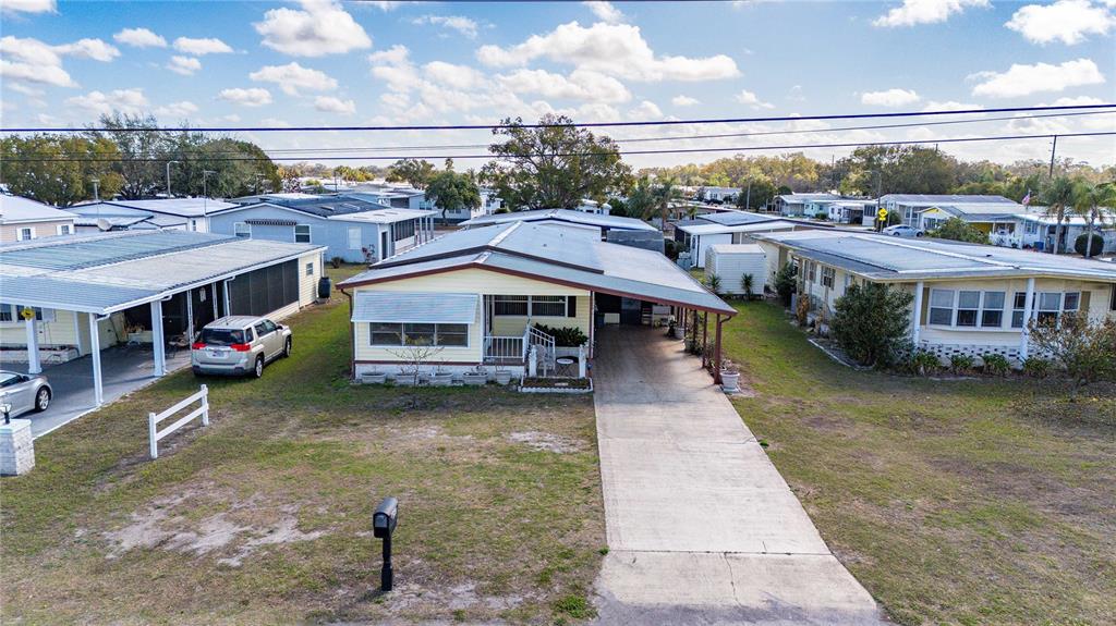 A single-story manufactured home features light yellow siding, a carport, and a front lawn — 5250 DEAN DAIRY ROAD, ZEPHYRHILLS, FL