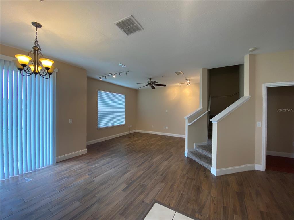 An open living area features wood-look flooring, a ceiling fan, and a carpeted staircase — 6660 S GOLDENROD ROAD UNIT 126B, ORLANDO, FL