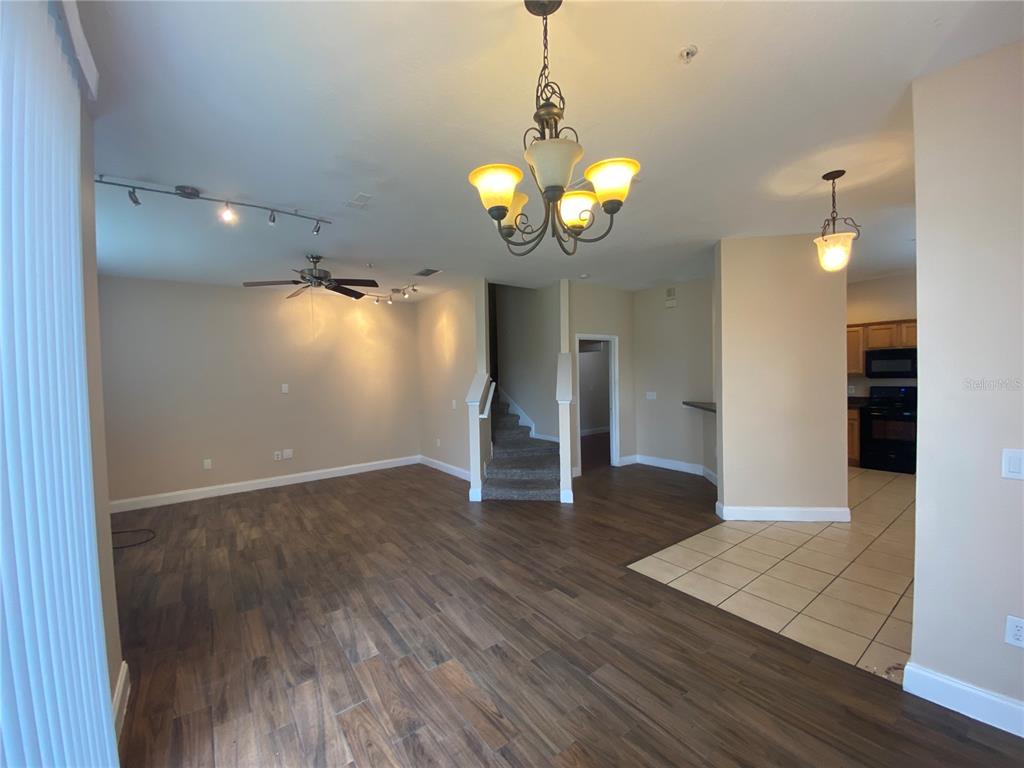 An open-concept living area features wood-look flooring, a chandelier, a ceiling fan, and carpeted stairs — 6660 S GOLDENROD ROAD UNIT 126B, ORLANDO, FL