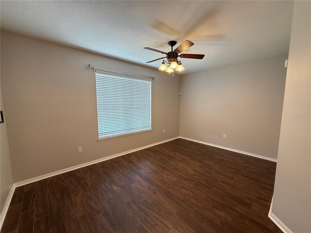 An empty bedroom features dark wood-look flooring, light gray walls, and a ceiling fan — 2260 TRADEWINDS DRIVE, KISSIMMEE, FL