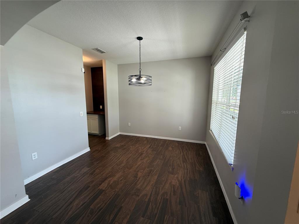 A dining area features dark wood-look flooring, light gray walls, and a modern metal chandelier — 2260 TRADEWINDS DRIVE, KISSIMMEE, FL