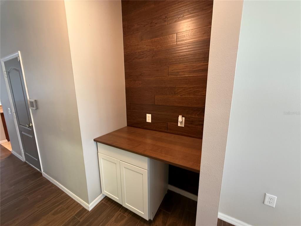 A built-in desk with white cabinets and a wood-paneled accent wall in a room — 2260 TRADEWINDS DRIVE, KISSIMMEE, FL