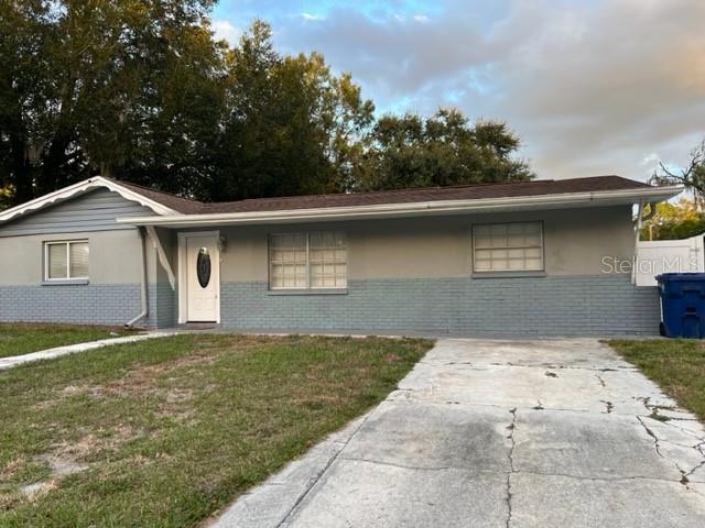 A single-story house with a gray brick exterior, a white front door, and a concrete driveway — 4926 BILLY DIRECT LANE, LUTZ, FL