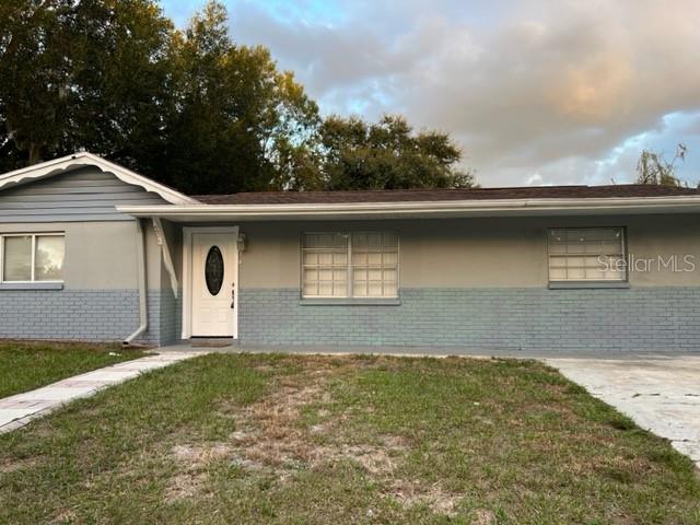 A single-story house features a light-colored brick exterior, a white front door, and two windows — 4926 BILLY DIRECT LANE, LUTZ, FL