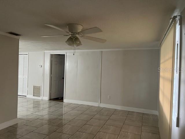 A room with light-colored walls, tiled flooring, a ceiling fan, and a doorway — 4926 BILLY DIRECT LANE, LUTZ, FL