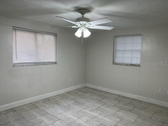 A bedroom features light gray walls, a ceiling fan, and light-colored tile flooring — 4926 BILLY DIRECT LANE, LUTZ, FL