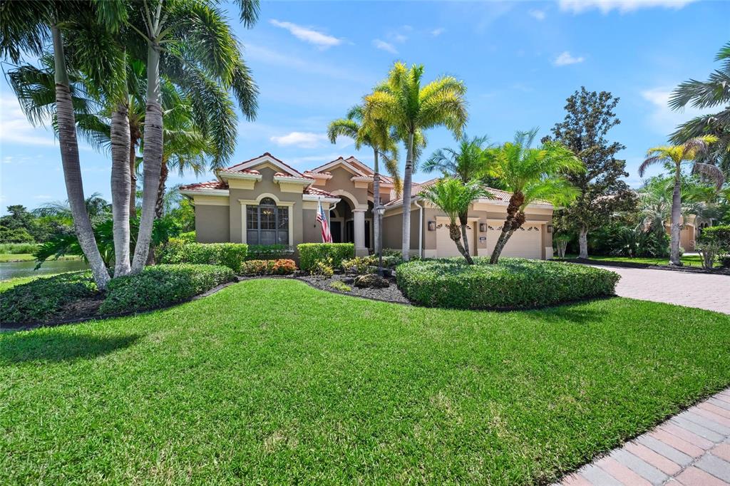 A single-story house with a tiled roof, palm trees, and a manicured lawn — 4665 TUSCANA DRIVE, SARASOTA, FL