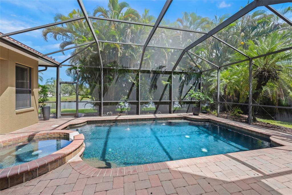 A screened-in patio features a swimming pool, a raised hot tub, and brick paver decking — 4665 TUSCANA DRIVE, SARASOTA, FL