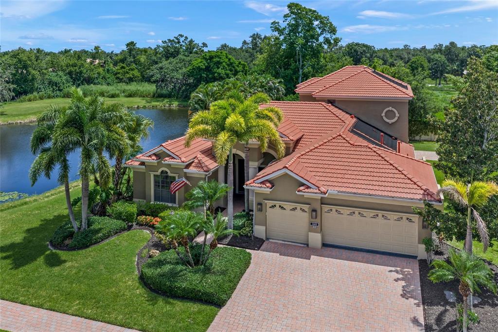 An aerial view of a single-story house with a red tile roof and a lake — 4665 TUSCANA DRIVE, SARASOTA, FL
