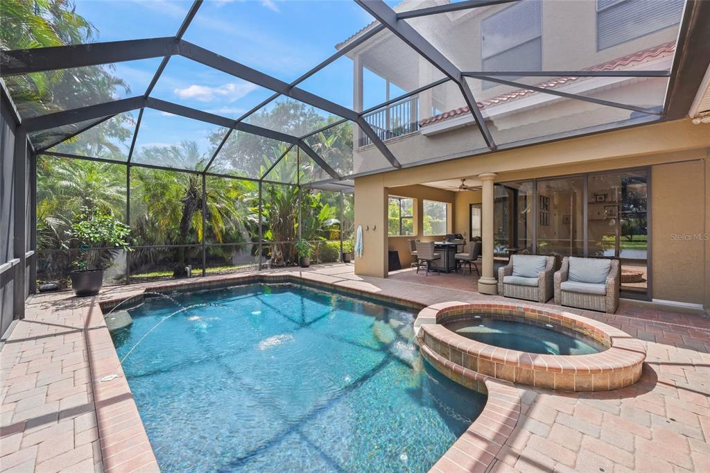 A screened-in patio features a swimming pool, a raised hot tub, and outdoor seating — 4665 TUSCANA DRIVE, SARASOTA, FL